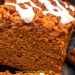 A close-up of a thick slice of pumpkin coffee cake, topped with streusel and white icing, is surrounded by cinnamon sticks and star anise. This pumpkin coffee cake looks perfectly spiced for autumn.