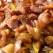 A close-up of Baked Brie topped with cooked bacon pieces and chopped apples, all covered in a brown, glossy sauce.