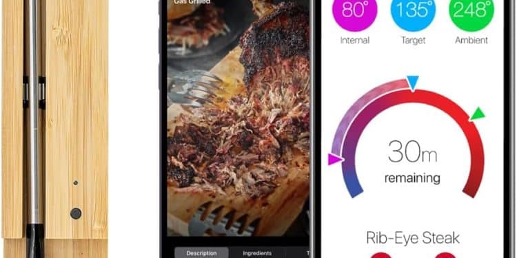 A MEATER+ Smart Meat Thermometer in a wooden charging case sits beside two smartphones displaying the MEATER app, showcasing cooking details and a temperature progress screen for a rib-eye steak.