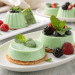 Green panna cotta desserts in a mint green color, topped with fresh mint leaves and assorted berries—raspberries, blackberries, and blueberries—served on white plates, showcase the elegance of Italian desserts.