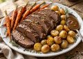 Sliced tender beef pot roast with carrots and potatoes on a white serving platter