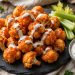 Crispy baked buffalo cauliflower bites glazed with buffalo sauce, drizzled with ranch, with celery and blue cheese dip