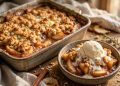 Homemade apple crisp with vanilla ice cream in a rustic baking dish