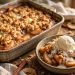 Homemade apple crisp with vanilla ice cream in a rustic baking dish