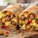 Breakfast burrito cut open showing eggs, sausage, cheese and potatoes