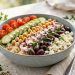Mediterranean quinoa power bowl with chickpeas, feta, tomatoes, cucumber, olives and tahini dressing