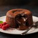 Molten chocolate lava cake with gooey chocolate center flowing out, served with fresh raspberries