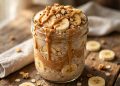 Mason jar of peanut butter banana overnight oats topped with banana slices, peanut butter drizzle and granola