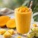 Tropical mango smoothie in a tall glass with fresh mango, pineapple, and lime