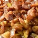 A close-up of Baked Brie topped with cooked bacon pieces and chopped apples, all covered in a brown, glossy sauce.