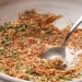 A close-up of a white bowl containing a flavorful meatloaf seasoning recipe—a blend of dry herbs and spices—with a silver spoon partially submerged, ready to elevate your next dish.