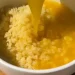A bowl of cooked rice is topped with a stream of raw beaten egg yolk on a wooden surface, reminiscent of traditional Japanese tamago kake gohan—a comforting dish akin to the warmth found in Italian Penicillin Soup.
