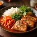 A plate with grilled tofu slices in sauce, inspired by recipes from Taiwan, garnished with chives, served alongside shredded white radish, julienned carrots, green peas, fresh herbs, and a lemon wedge on a wooden table.