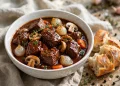 Classic beef bourguignon in a white bowl with pearl onions, mushrooms and carrots