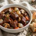 Classic beef bourguignon in a white bowl with pearl onions, mushrooms and carrots