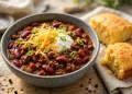 Bowl of beef chili con carne topped with sour cream, cheddar and green onions