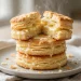 Tall golden flaky buttermilk biscuits, one split open with melting butter