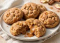 Caramel-stuffed apple cookies on a plate, one broken open showing gooey caramel