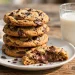 Stack of golden chewy chocolate chip cookies with melted chocolate on a white plate
