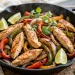 Sizzling chicken fajitas with peppers and onions in a cast-iron skillet