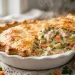 Creamy chicken pot pie with golden flaky crust in a white pie dish