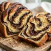 Sliced chocolate babka with dramatic dark fudgy ribbons marbled through golden crumb on a wooden board