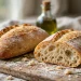 Two crusty ciabatta loaves with golden crackled crust, one sliced showing open airy crumb