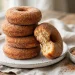 Baked cinnamon sugar donuts stacked on a plate, sparkling with cinnamon sugar coating