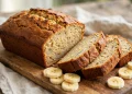 Golden-brown banana bread loaf with crackled top, sliced to show a moist tender crumb