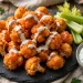 Crispy baked buffalo cauliflower bites glazed with buffalo sauce, drizzled with ranch, with celery and blue cheese dip