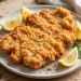 Crispy golden pork schnitzel with lemon wedges and fresh parsley on a plate