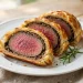 Sliced beef Wellington with medium-rare center wrapped in golden puff pastry
