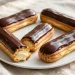 Elegant eclairs with glossy chocolate glaze arranged on a white platter