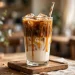Tall glass of homemade iced caramel macchiato with layered milk and espresso, caramel drizzle, and a straw