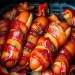 Air fryer hot dogs wrapped in crispy bacon, topped with ketchup and sprinkled with chopped herbs, arranged perfectly in the basket for a tasty twist on a classic favorite.