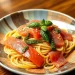 A bowl of spaghetti topped with slices of raw salmon, green basil leaves, sesame seeds, and dollops of green pesto is served on a patterned plate on a wooden table—a fresh taste from Jalbiteworldfood.