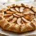 Rustic spiced pear galette with golden flaky crust on parchment paper