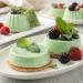Green panna cotta desserts in a mint green color, topped with fresh mint leaves and assorted berries—raspberries, blackberries, and blueberries—served on white plates, showcase the elegance of Italian desserts.