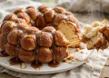 Golden brown monkey bread in a Bundt shape on a plate with caramel dripping