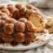 Golden brown monkey bread in a Bundt shape on a plate with caramel dripping