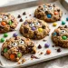 Monster Halloween cookies with candy eyes, M&Ms and chocolate chips on a baking sheet
