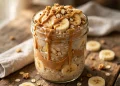 Mason jar of peanut butter banana overnight oats topped with banana slices, peanut butter drizzle and granola