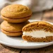 Pumpkin whoopie pies with cream cheese filling stacked on a white plate