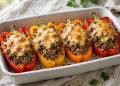 Stuffed bell peppers with beef, rice and melted cheese in a baking dish