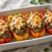 Stuffed bell peppers with beef, rice and melted cheese in a baking dish