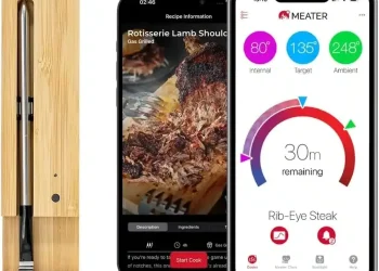 A MEATER+ Smart Meat Thermometer in a wooden charging case sits beside two smartphones displaying the MEATER app, showcasing cooking details and a temperature progress screen for a rib-eye steak.