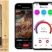 A MEATER+ Smart Meat Thermometer in a wooden charging case sits beside two smartphones displaying the MEATER app, showcasing cooking details and a temperature progress screen for a rib-eye steak.