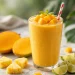 Tropical mango smoothie in a tall glass with fresh mango, pineapple, and lime